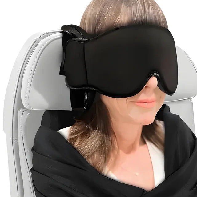 A traveler in a seat with the eye mask on and the body sling draped over her