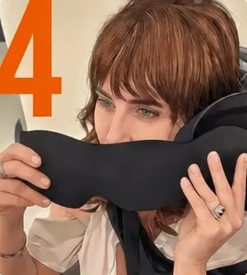 A traveler holding the eye mask up to attach it to the head pillow